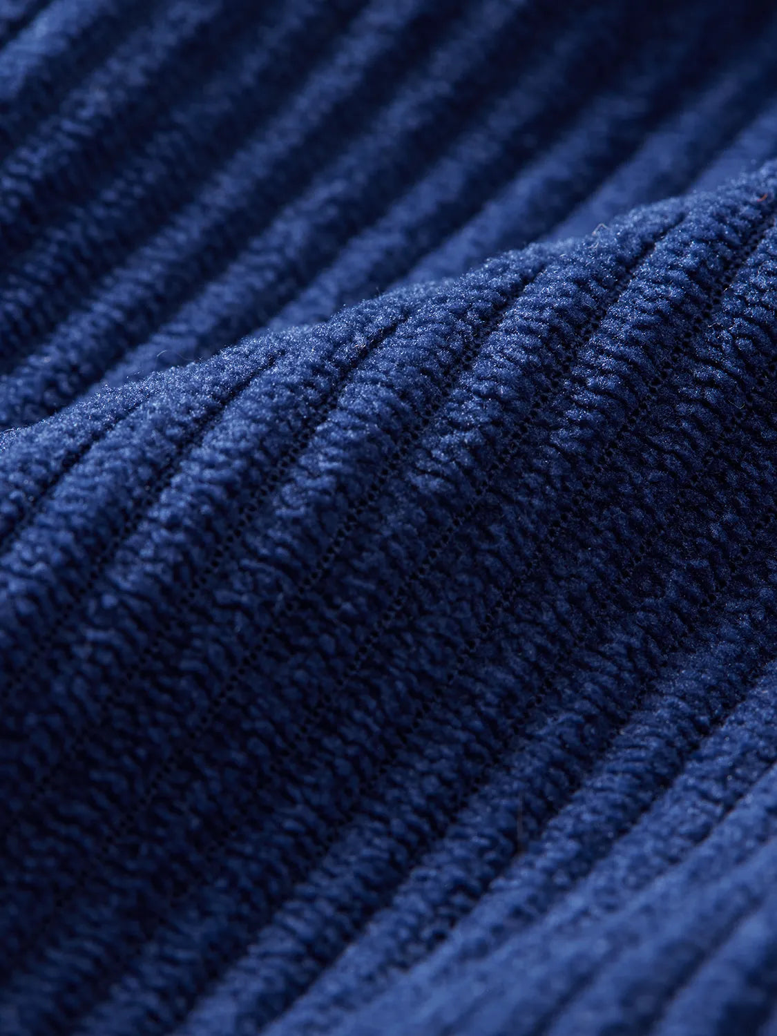 Close-up of navy corduroy fabric showing ribbed texture and vertical cord pattern detail.