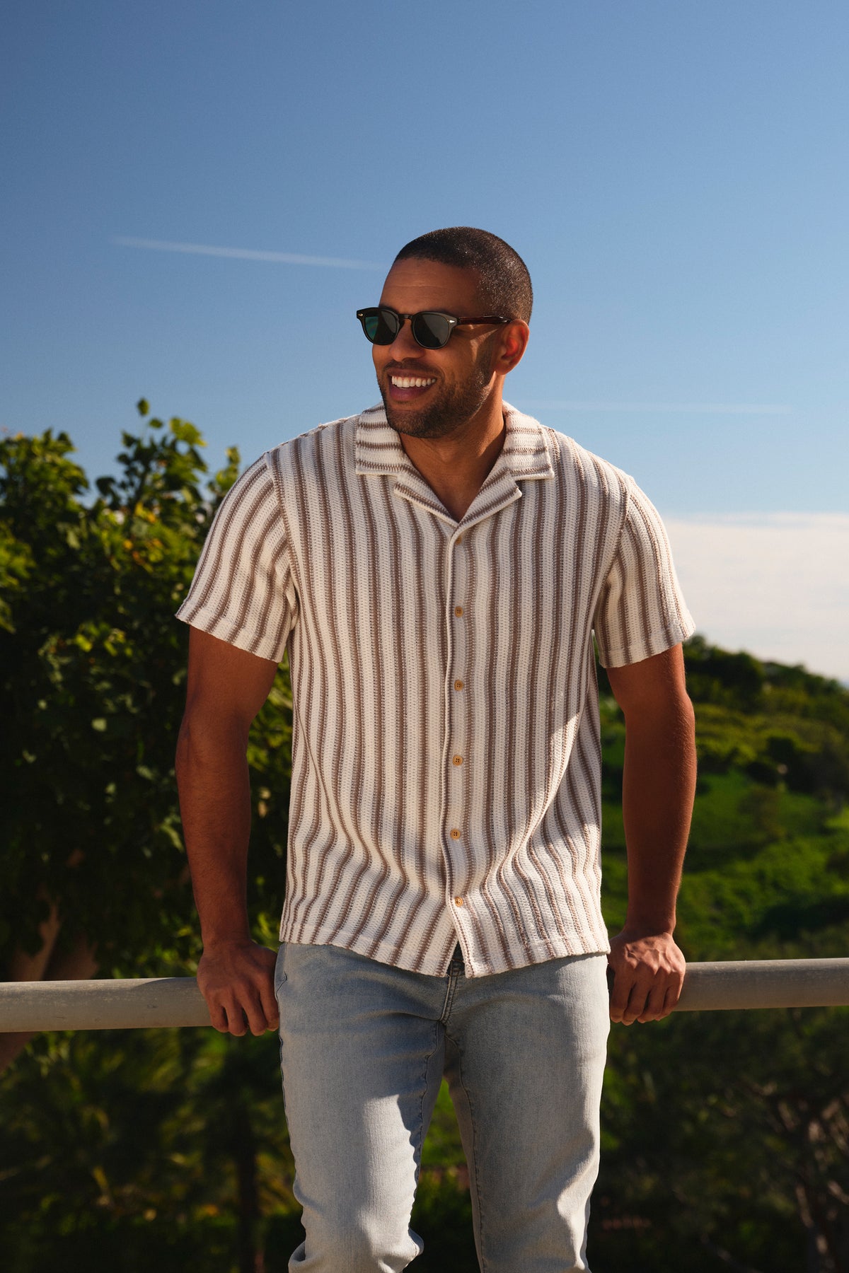 Man wearing a short-sleeved crochet shirt with vertical stripes in natural and white tones.