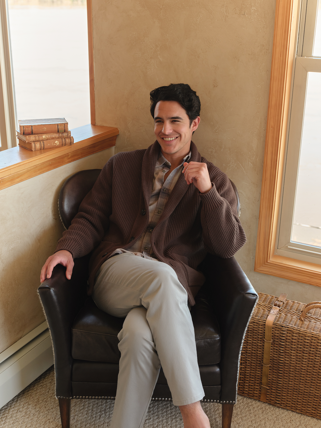 Man wearing dark brown ribbed cardigan sweater seated in leather chair.