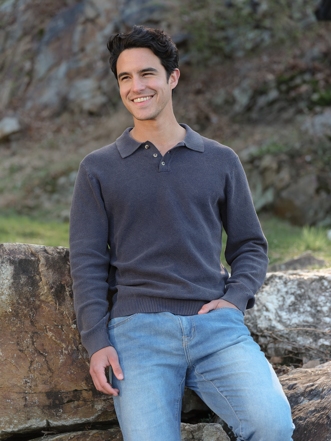 Man wearing a gray long sleeve polo shirt with a collar and buttons, paired with light blue jeans.