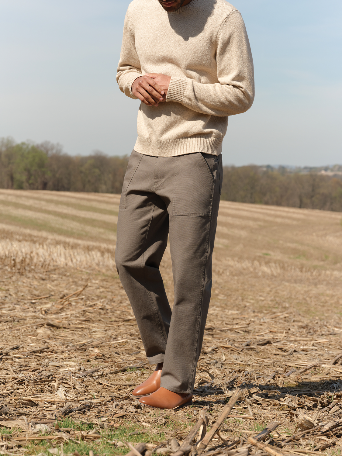 Person wearing olive cargo pants with multiple pockets standing in an open field.