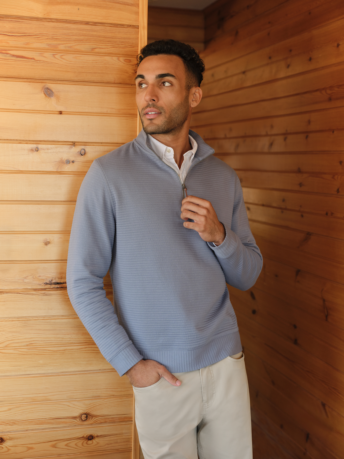 Man wearing a navy quarter zip pullover with textured fabric and white collared shirt underneath.