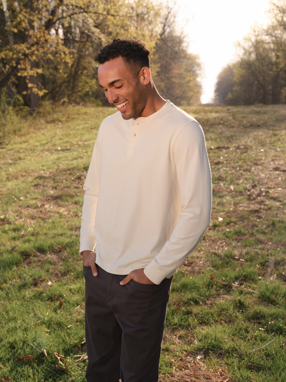 Man wearing a cream-colored long-sleeve henley shirt with button placket and dark pants.
