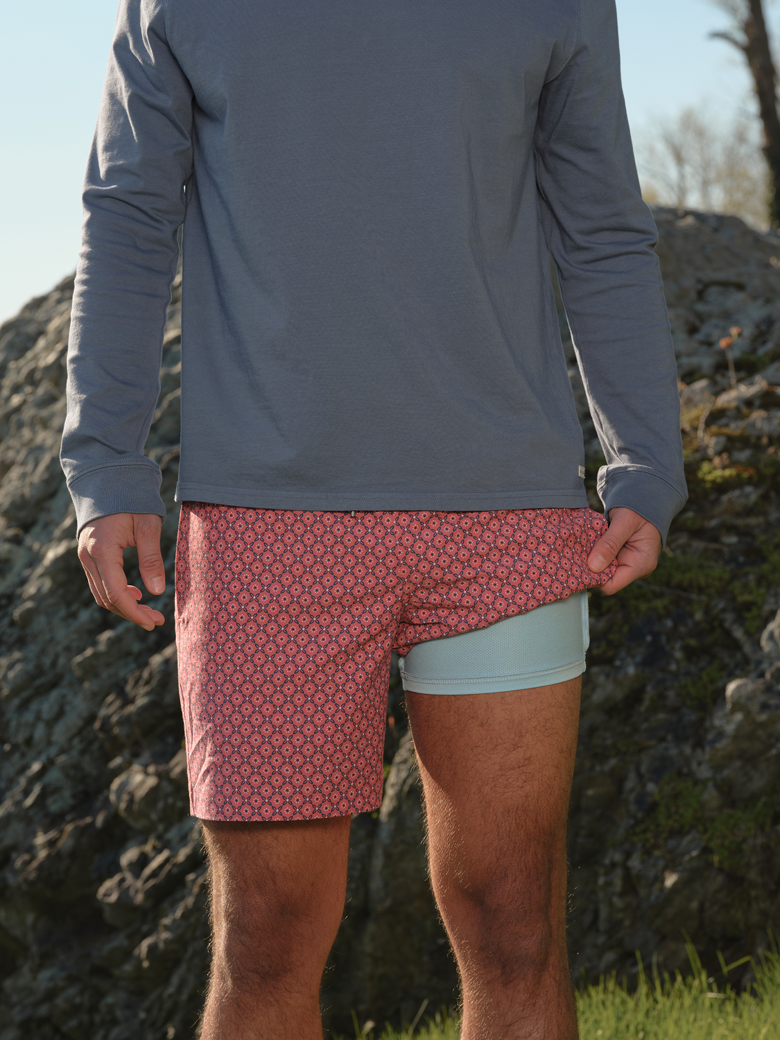 Man wearing red bandana patterned swim trunks with light blue undershorts and navy long-sleeved shirt.