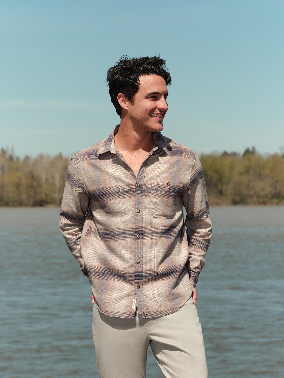 Man wearing sand ombre striped flannel shirt with button front and chest pocket over cream pants.