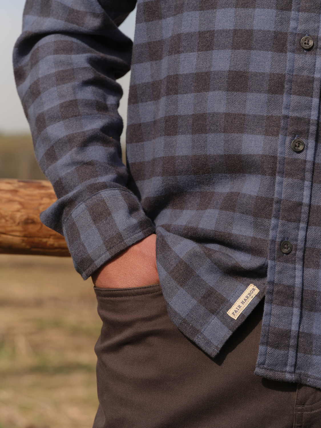 Blue and gray plaid flannel shirt with button front and rolled sleeves on wearer.